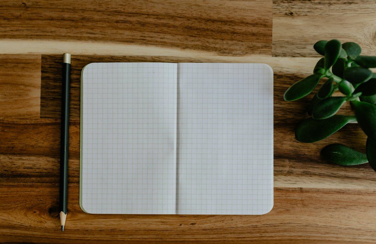 Carnet quadrillé ouvert et crayon posés sur un bureau