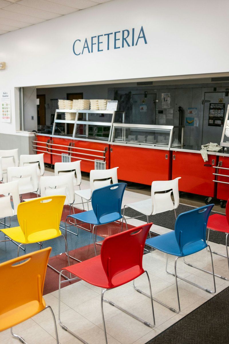 Salle de restaurant collectif vide, avec des tables et des chaises de couleurs vives