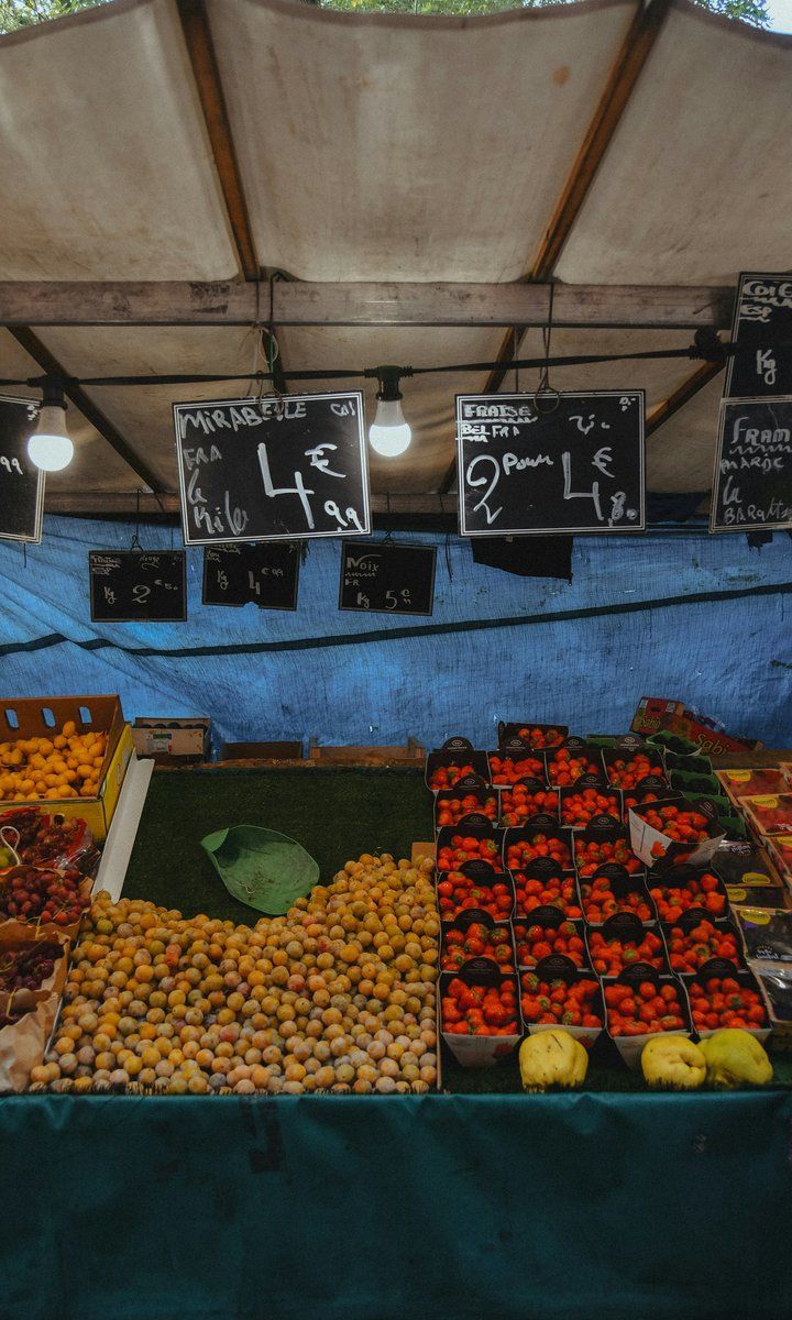 Étal de fruits sur un marché parisien, prix écrits à la craie sur des ardoises