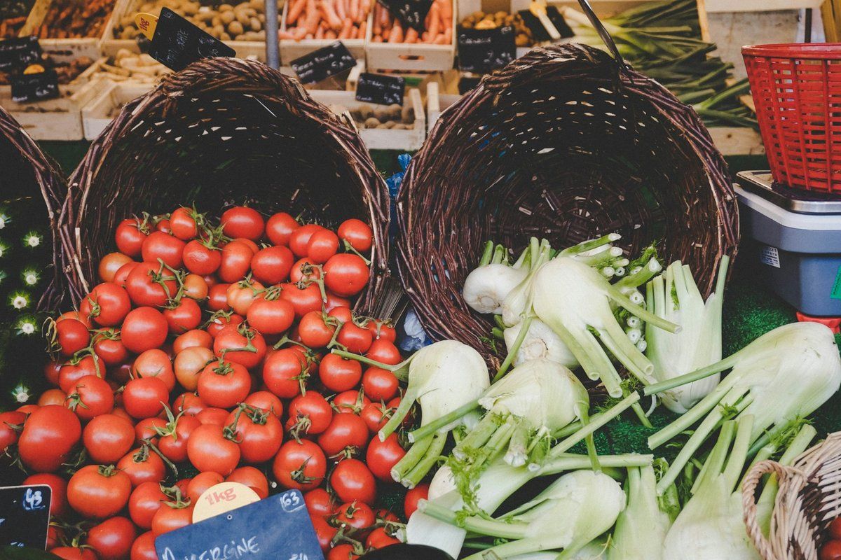 Paniers de tomates et de bulbes de fenouil sur un étal de marché