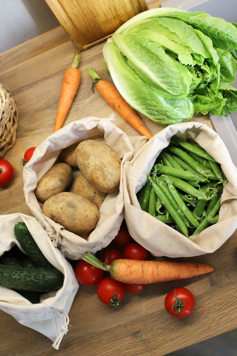 Sacs en tissu de pommes de terre et de haricots verts, carottes et tomates sur une table